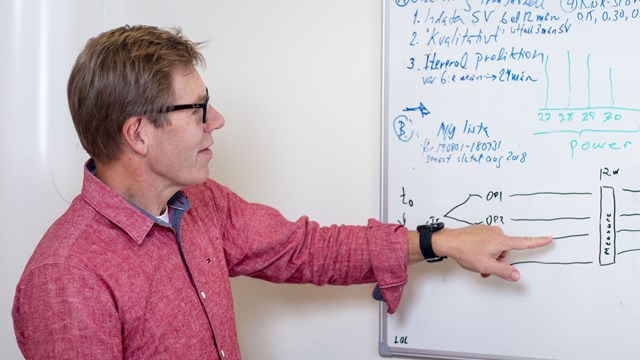 Statistikern Mats Fredrikson pekar på en whiteboardtavla.