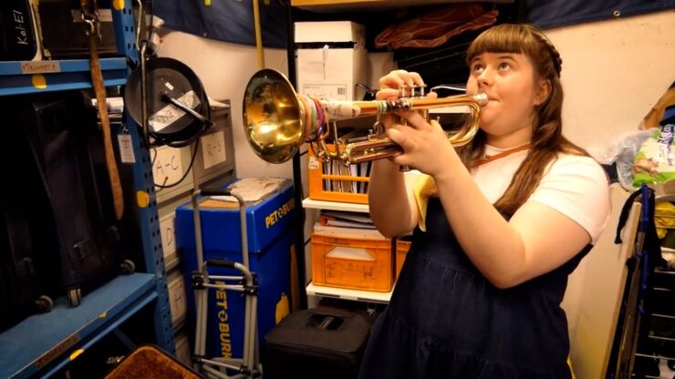 Kvinnlig trumpetspelande student i stökigt förråd