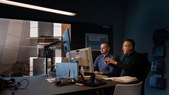 Två forskare framför en dator i ett mörkrum.