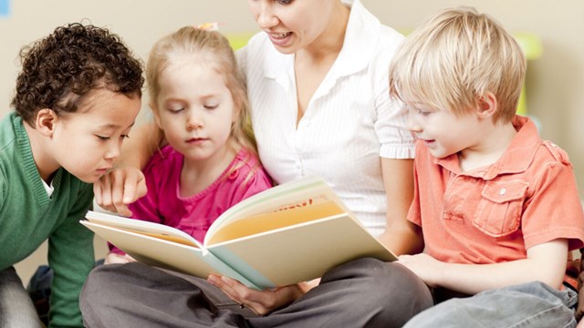 En lärare i förskolan läser en saga för en grupp barn.
