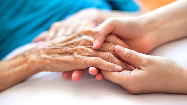 Händer håller om varandra, äldre patient och vårdare.