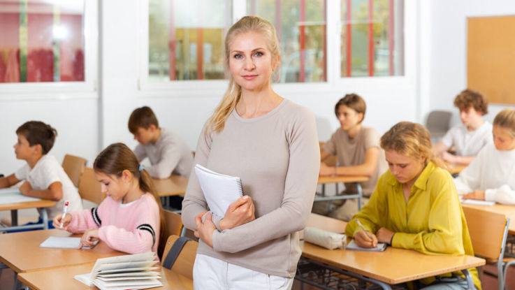 Kvinnlig pedagog håller anteckningar med ett fokuserat uttryck i en skolmiljö